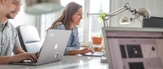 Два человека работают за ноутбуками в офисе