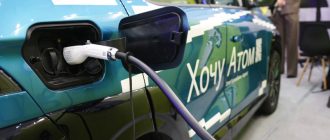 Электромобиль Атом синего цвета на зарядной станции крупным планом